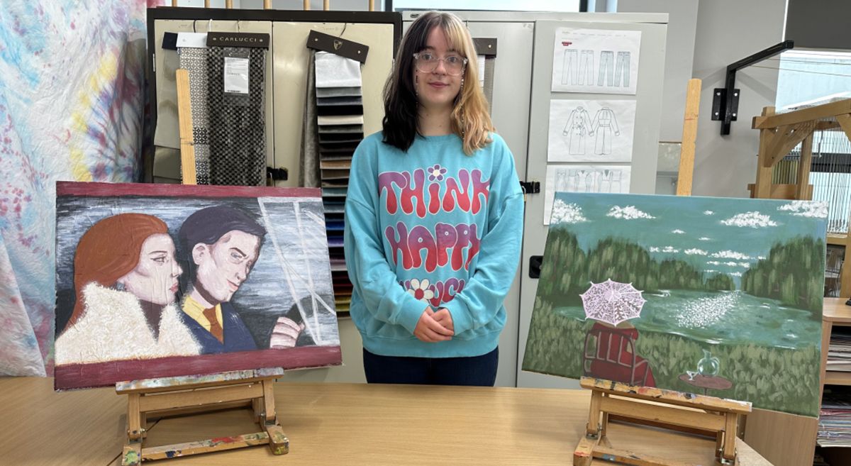 Picture of Samantha Brown standing between two of her art pieces. 